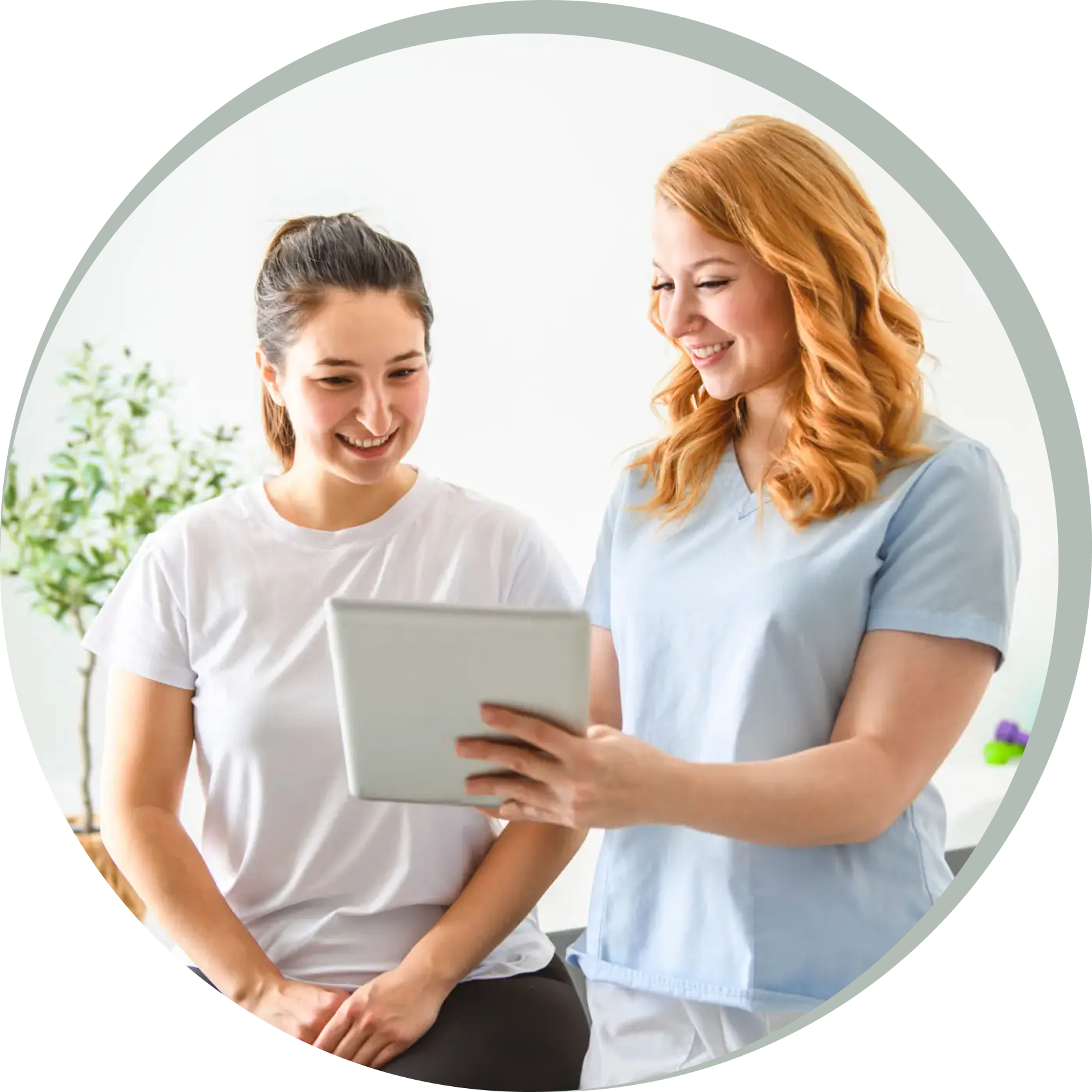 Two women smiling and looking at a tablet together.