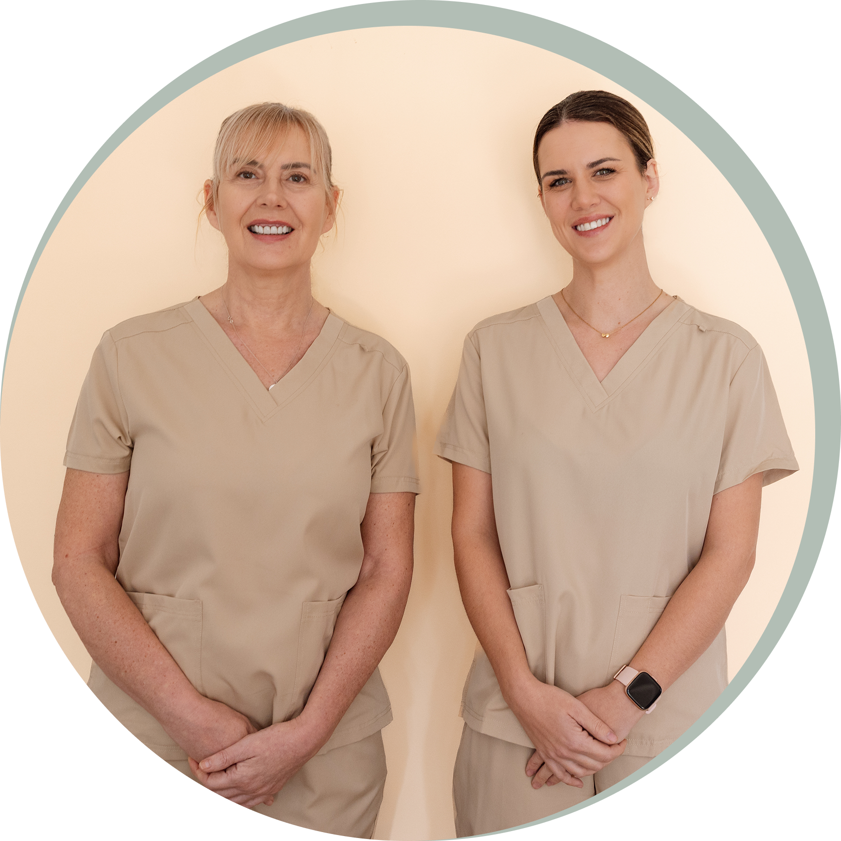 Two smiling healthcare professionals in scrubs standing side by side.